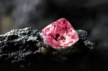 Argyle Pink diamond rough cut on the surface of a black rock