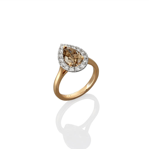 Dress ring with a pear-shaped champagne diamond and smaller white surrounding diamonds photographed on side view on a white background