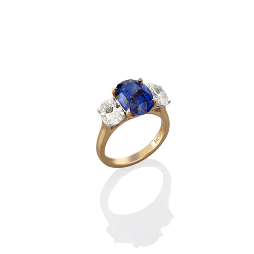 Yellow Gold dress ring with central oval shaped blue sapphire flanked on either side with oval shaped white diamonds, image showing side view