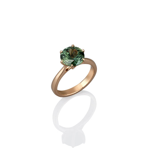 Yellow gold ring with a green sapphire gemstone on a white background
