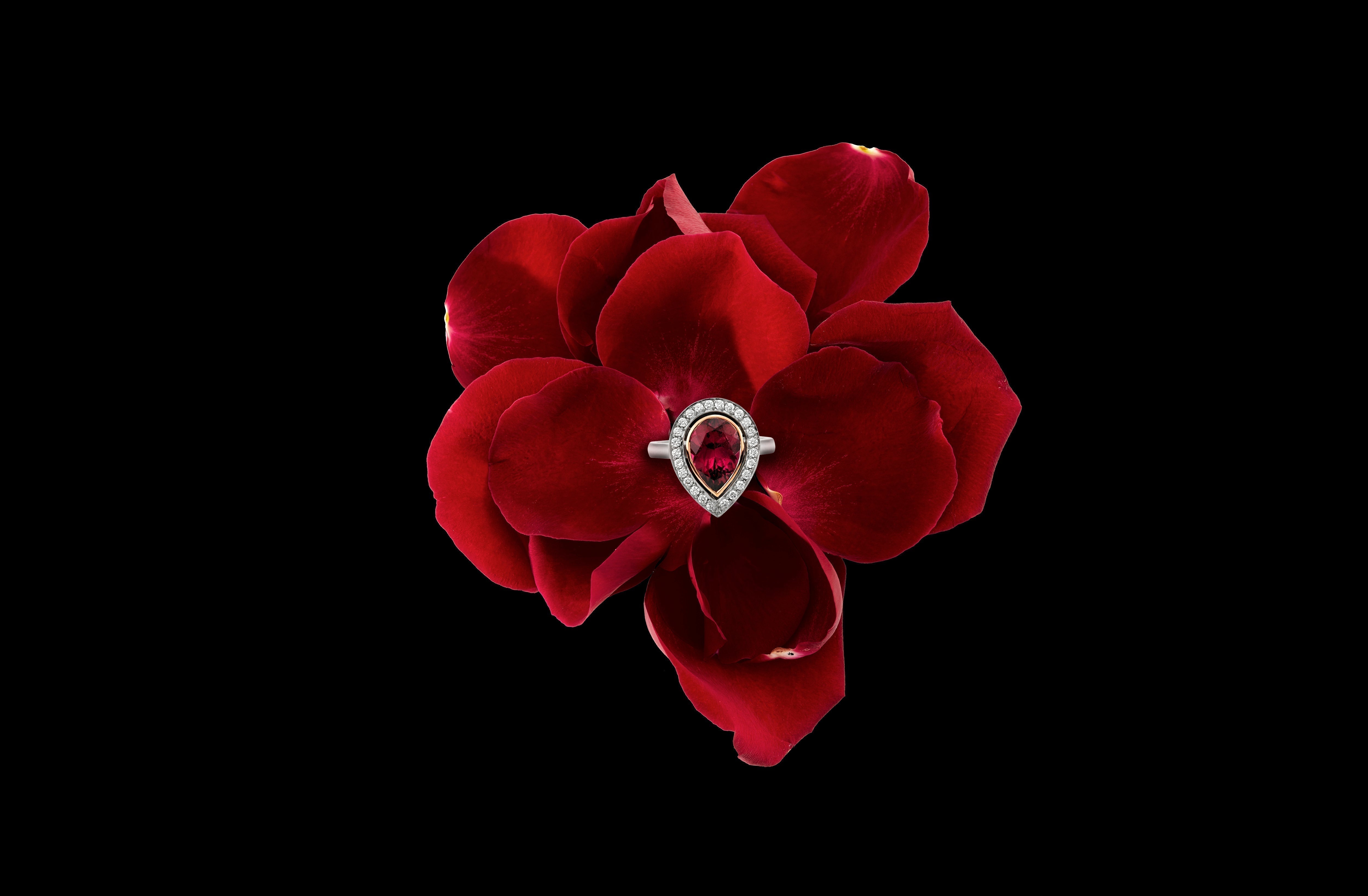 A ruby and diamond ring set on a deep red flower
