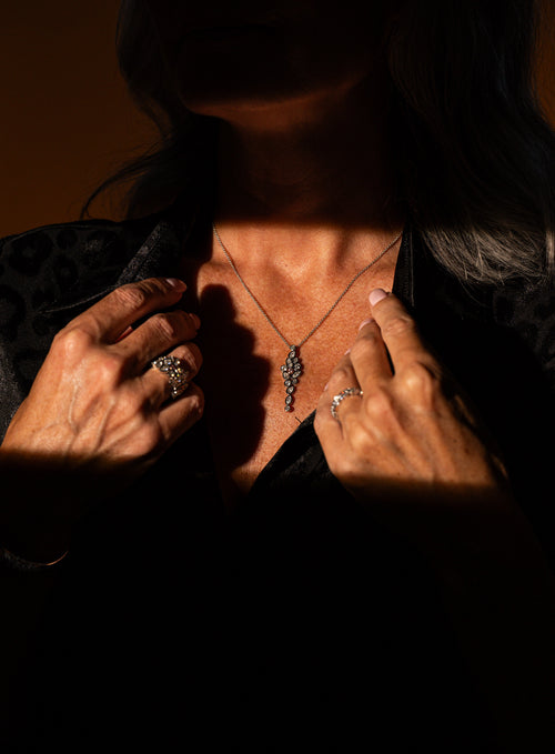 A shadow of light shining across the neckline of a woman showing a drop necklace with diamonds