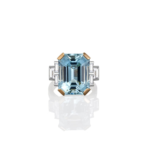 Ring with a large blue aquamarine gemstone and gold accents on a white background