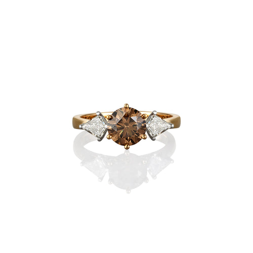 Gold ring with a central argyle champagne diamond stone and smaller white diamonds set on either side, photographed on white background and showing from the top of the ring