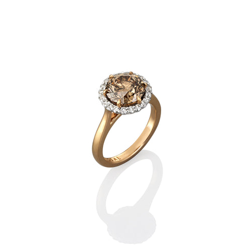 Gold ring with a large argyle champagne diamond and smaller white diamonds photographed on a white background