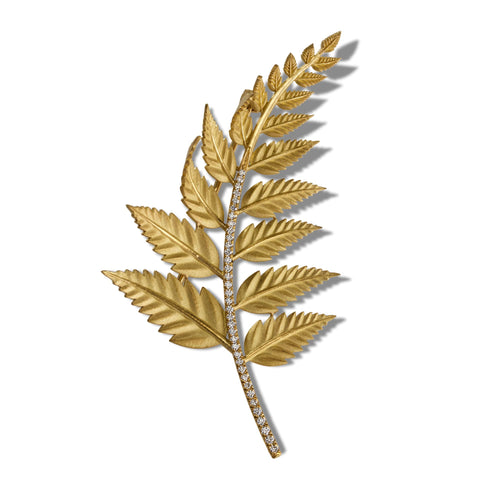 Gold fern brooch with sparkling crystal accents on a white background.