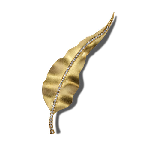 Gold gum leaf brooch with sparkling crystal accents on a white background.