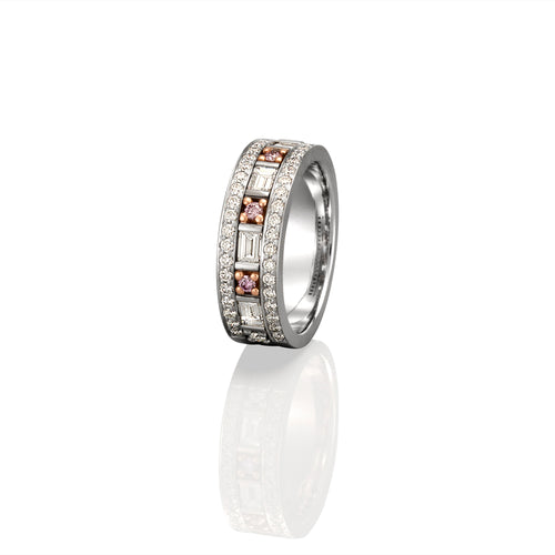 White gold ring encrusted with white diamonds and pink sapphires standing upright on its side. The ring is on a high white background with a shadow of the ring showing in the foreground. 