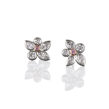 Pair of flower-shaped stud earrings with diamonds and central rare argyle pink diamond. Image is set on a white background
