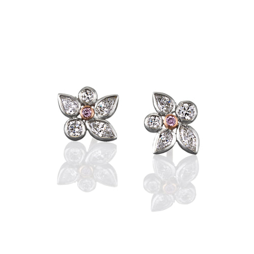 Pair of flower-shaped stud earrings with diamonds and central rare argyle pink diamond. Image is set on a white background