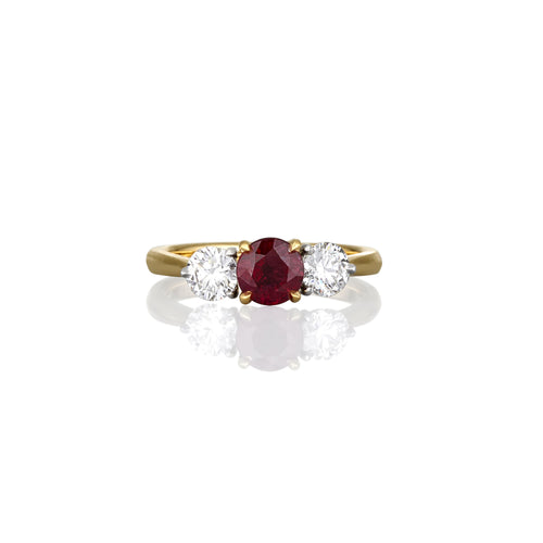 Yellow gold ring with a brilliant cut ruby gemstone and two smaller white diamonds. 