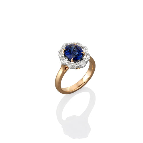 Yellow fold ring with central blue halo shaped sapphire gemstone. Surrounded by oval cut diamonds