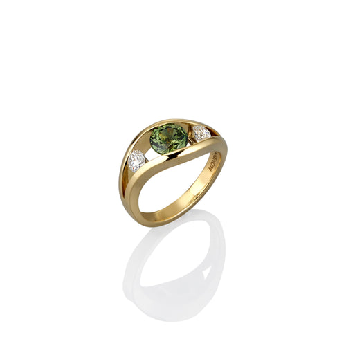Gold ring with a green sapphire gemstone and two smaller white diamonds on either side, shown her from the side view