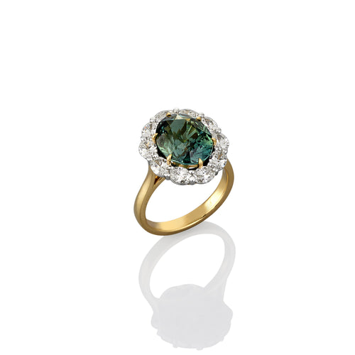 Yellow gold dress ring with central green halo sapphire. Smaller white diamonds surround the central stone. Showing side view