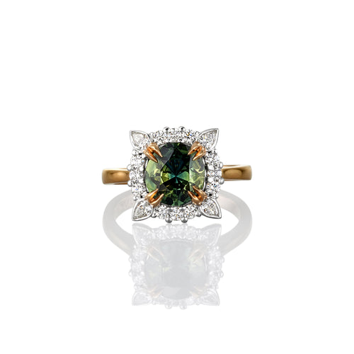 Ring with a green sapphire gemstone and gold accents shown from above on a white background
