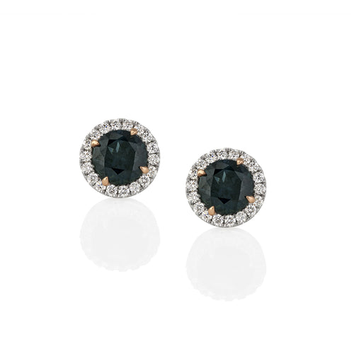 Pair of earrings with green sapphire gemstones and diamond-studded halo shown on a white background.
