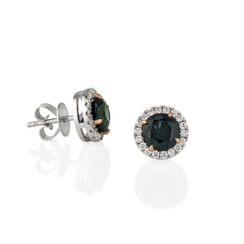 Pair of earrings with green sapphire gemstones and diamond-studded halo shown on a white background with a view from the side showing the stud clasp