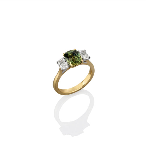 Yellow gold ring with a green gemstone and two smaller diamonds on a white background shown from the side view
