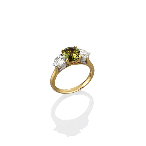 Gold ring with a green sapphire gemstone and white diamonds showing on a white background