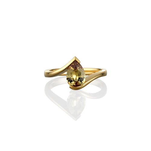 Gold ring with a pear-shaped yellow sapphire on a white background