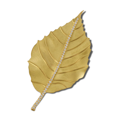 Gold single leaf brooch with sparkling crystal accents on a white background.