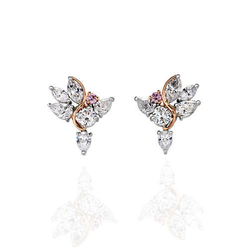 Earrings with pear shaped white diamonds and brilliant cut pink sapphire on a glass white backdrop with a shadow in the foreground