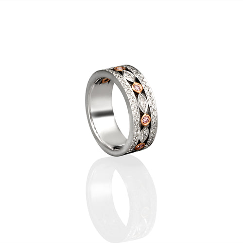 Photographed on its side a white gold ring with a wide band. Diamonds and Argyle Pink Diamond encrusted.