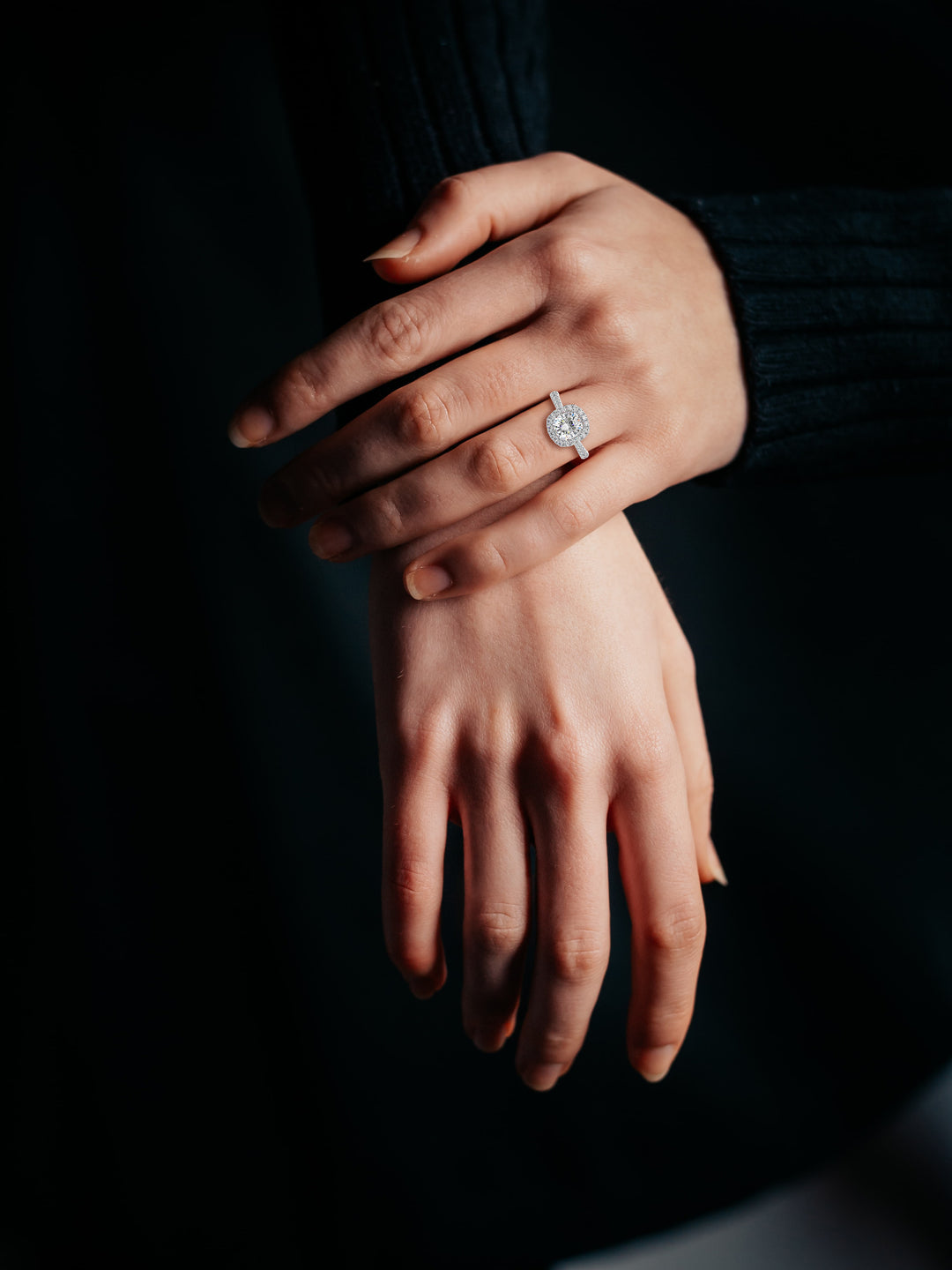Cushion cut diamond Halo engagement ring with diamond set band on woman's hand