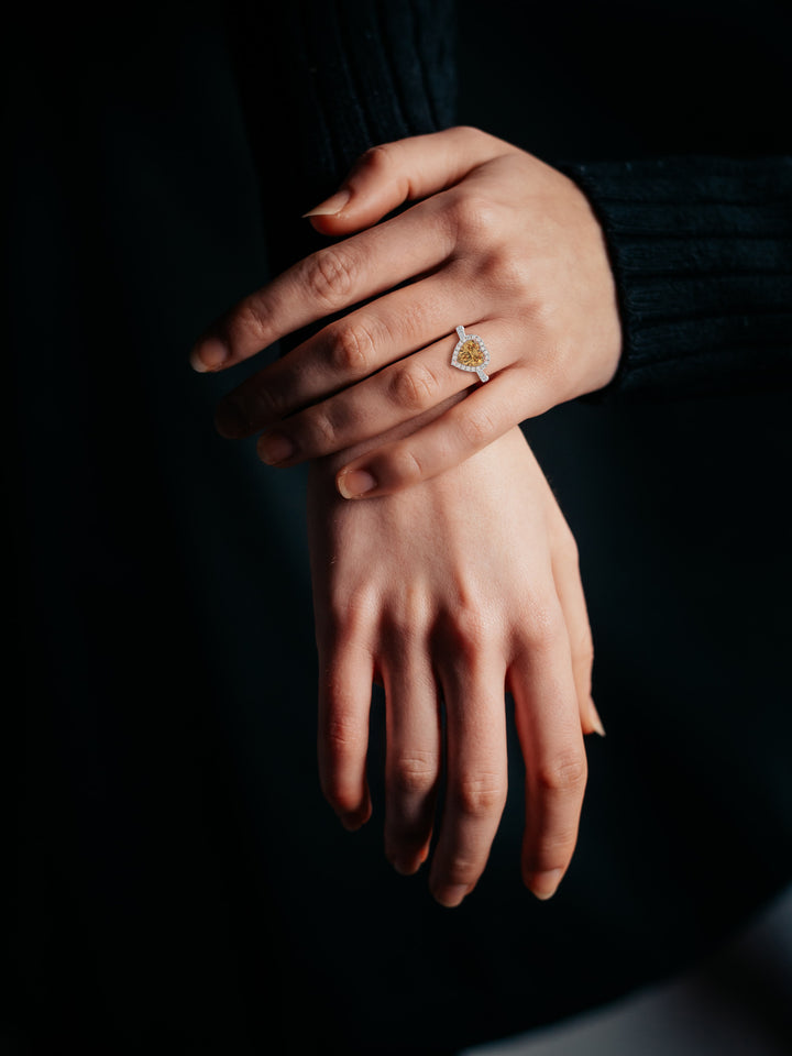 Heart shape champagne diamond halo ring with diamond set band on woman's hand 