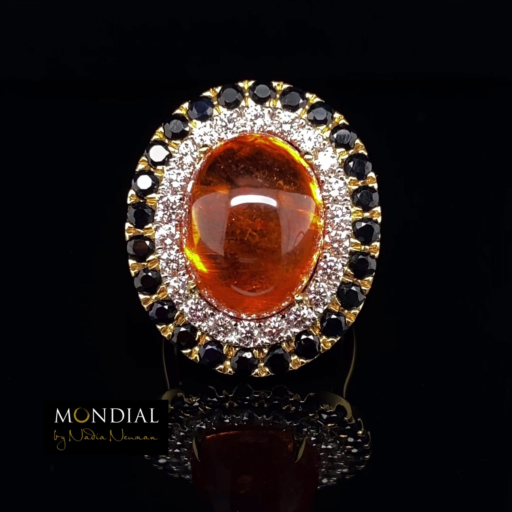 Video of the Mondial by Nadia oval cabochon Spessartite garnet, sapphire and diamond halo engagement ring on yellow gold band.