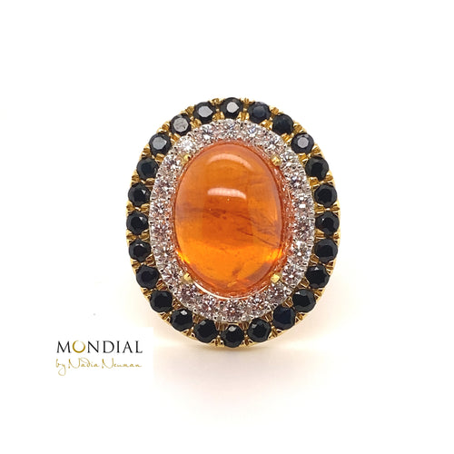 The Mondial by Nadia oval cabochon Spessartite garnet, sapphire and diamond halo engagement ring on yellow gold band.