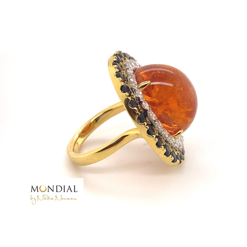 Side view of the Mondial by Nadia oval cabochon Spessartite garnet, sapphire and diamond halo engagement ring on yellow gold band.