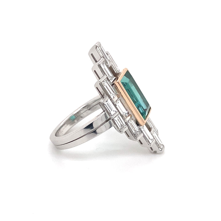 A side view of the Manhattan design baguette cut tourmaline and diamond ring on white gold band on a white background.